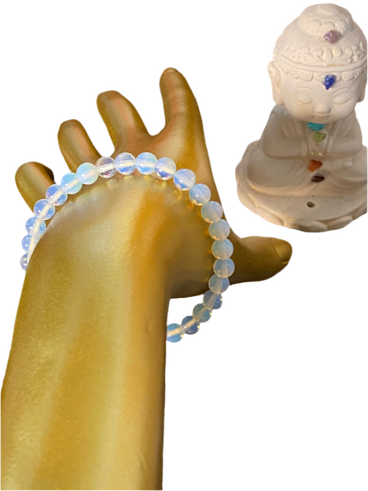 Opalite Beaded String Bracelet 6mm on hand near a meditating figure, showcasing soft glowing hues and spiritual clarity benefits.