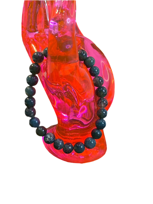 Green Jasper Beaded String Bracelet on pink display, highlighting balance and confidence.