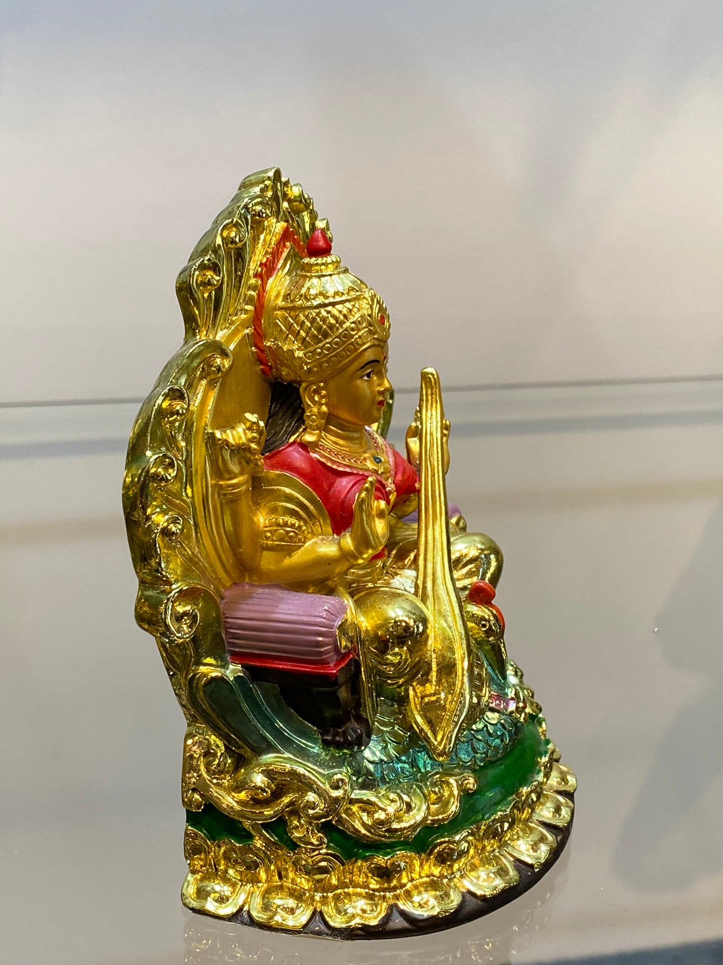 Golden Hindu Goddess Saraswati playing the Veena and sitting on a Swan