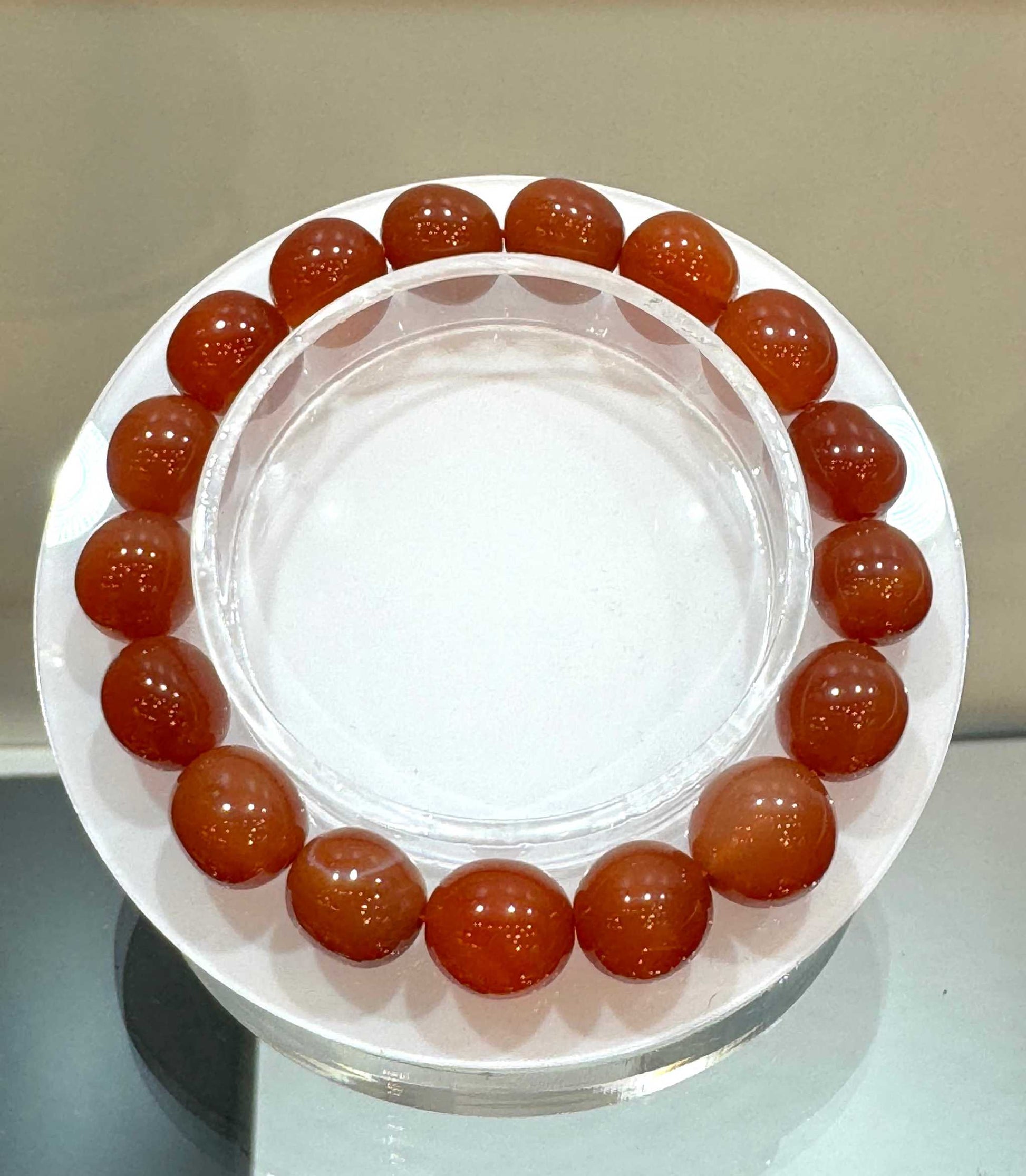 Fire Agate Gemstone Bracelet 8mm with warm, glowing beads displayed on a circular holder.