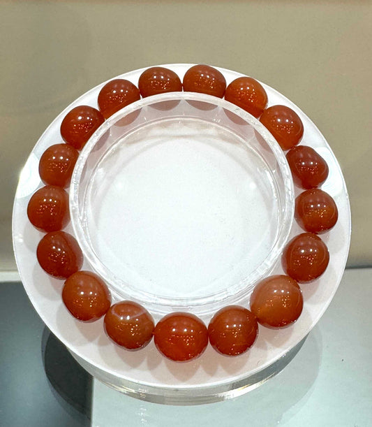 Fire Agate Gemstone Bracelet 8mm with warm, glowing beads displayed on a circular holder.