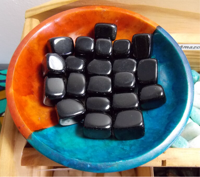 Black Obsidian Crystal Tumbled Cubes in a colorful dish, offering grounding energy.