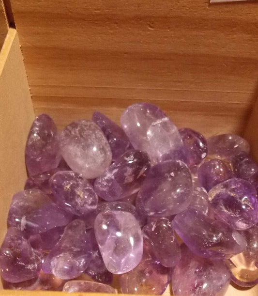 A collection of high-quality ametrine tumbled stones in a wooden box.