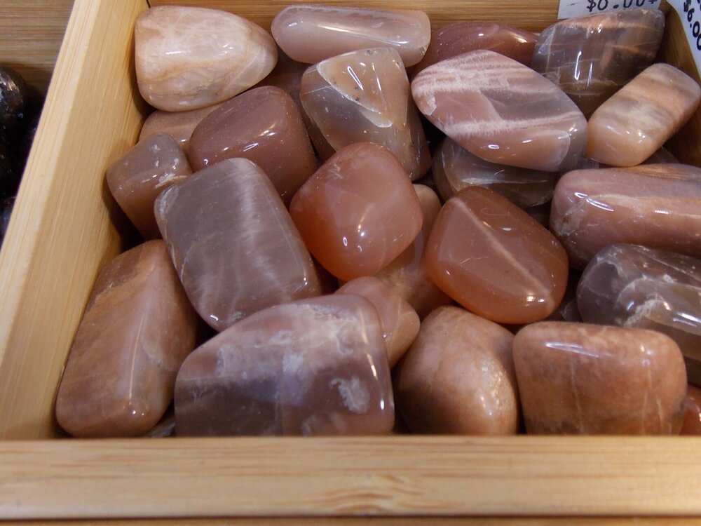 Moonstone tumbled stones in peach and brown hues, associated with intuition and self-development.