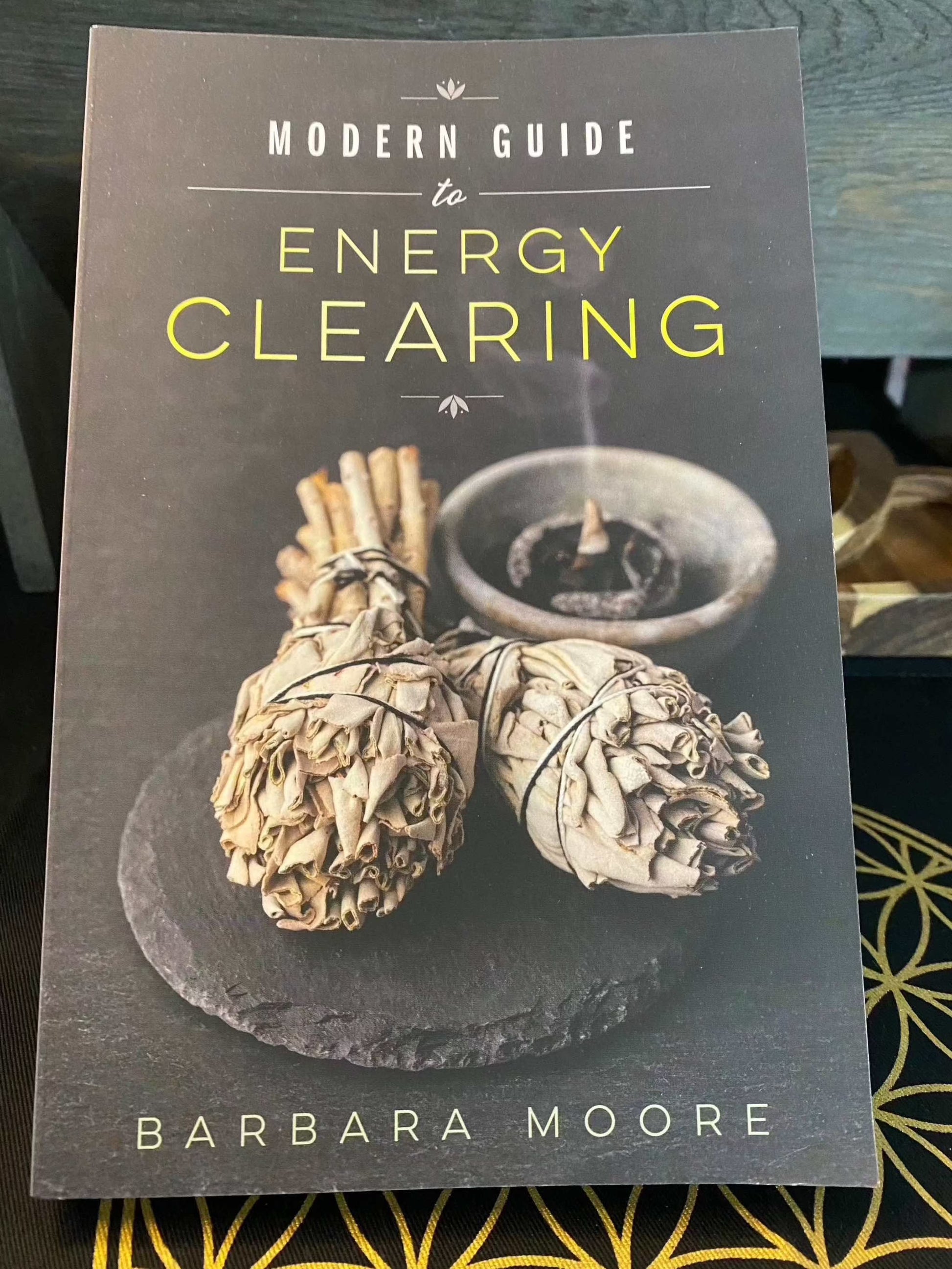 Modern Guide to Energy Clearing book by Barbara Moore with sage bundles on the cover.