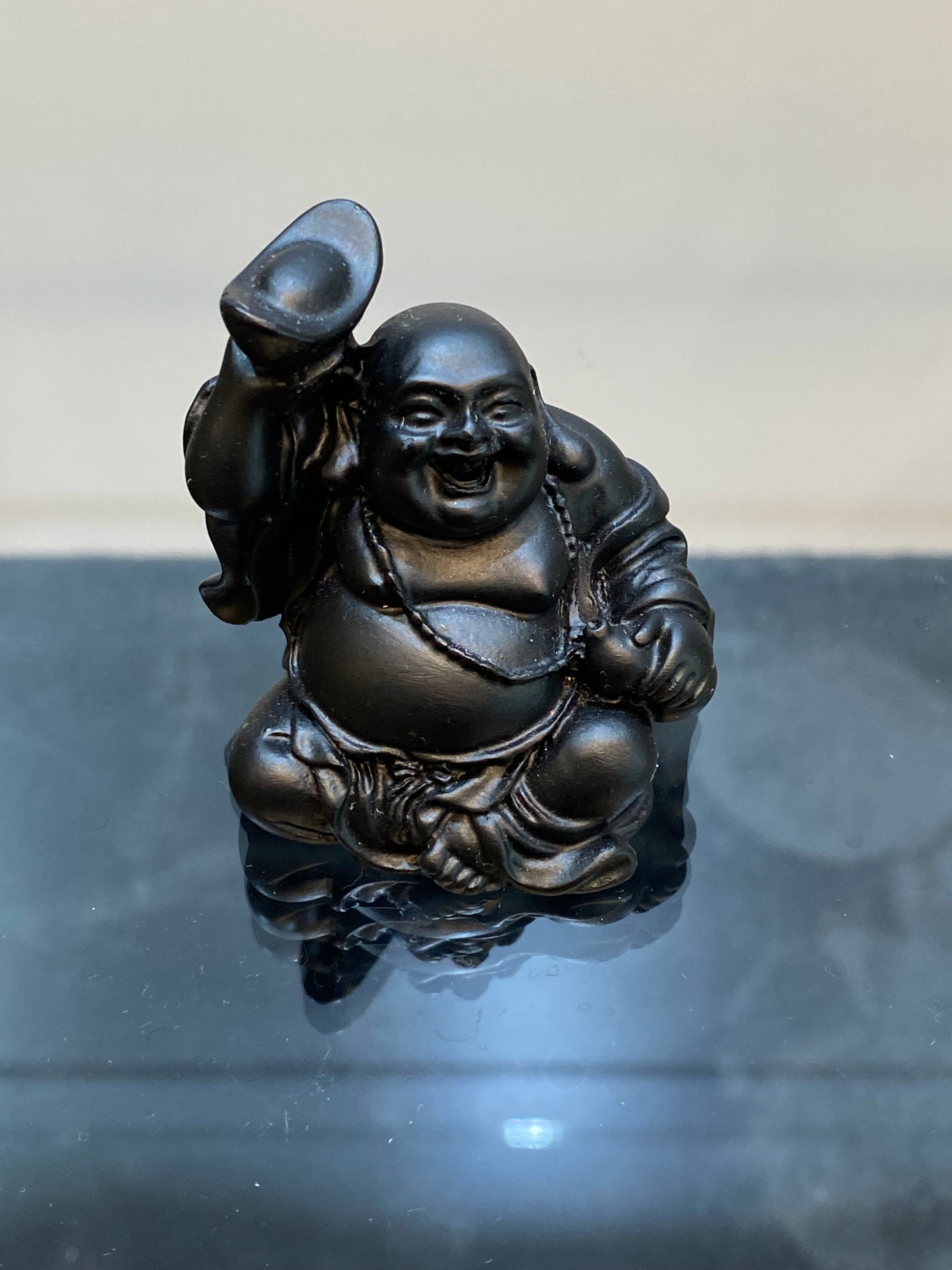 Black Laughing Buddha with Ingot and Gourd in his hands a symbol of abundance